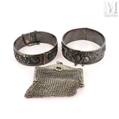 two silver bracelets and a chain purse on a white surface