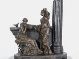 bronze statue of a woman sitting on a bench next to a bird