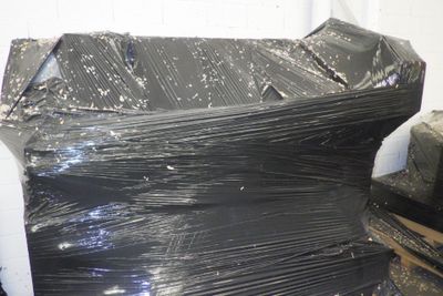 un gros tas de film plastique noir posé sur une pile de cartons