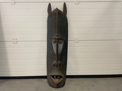 un masque en bois accroché au mur d'un garage
