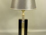 une lampe de table noire et dorée, surmontée d'un abat-jour argenté