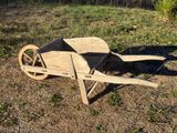 a wooden wheelbarrow sitting on the ground in the grass
