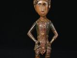 une figurine en bronze représentant un homme coiffé d'un chapeau et les mains sur les hanches