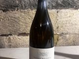 a bottle of wine sitting on a table next to a brick wall