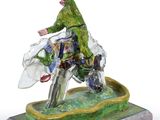 figurine of a man riding a horse on a green base