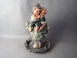 a figurine of a boy and a girl sitting on a tree branch