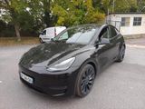 un SUV Tesla noir garé sur un parking à côté d'une camionnette blanche