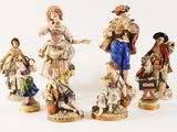 three figurines of people dressed in different styles of clothing