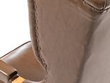 the back of a brown leather chair with a wooden foot rest