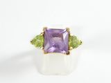 a close up of a ring with an amethorate and peridot stones