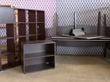several bookshelves and a desk in a room with a checkered wallpaper