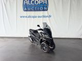 La moto est garée devant un panneau indiquant « Alcoba Auction ».