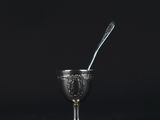 a silver cup with a spoon in it on a black background