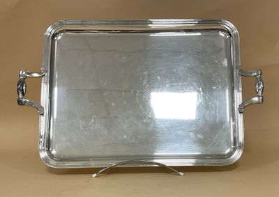 un plateau en argent muni de poignées, posé sur une table