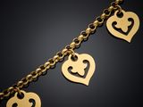 a close up of a gold bracelet with heart charms on it