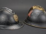 pair of antique fire helmets on a black background with a gray background