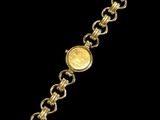 a close up of a gold bracelet with a coin on it