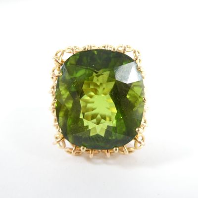 un gros plan d'une bague ornée d'une pierre verte sur un fond blanc