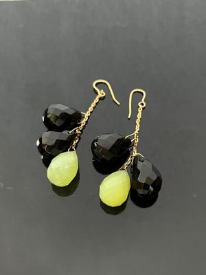 a pair of black and yellow earrings on a black surface