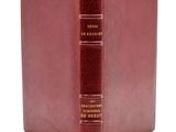 a red book with gold lettering sitting on top of a white surface