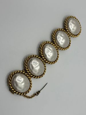 a close up of a gold bracelet with pearls on it