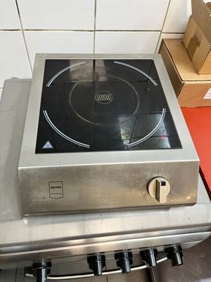 une cuisinière avec un brûleur posé dessus, dans une cuisine