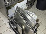 several pans are stacked on top of a metal shelf in a kitchen