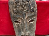a wooden mask on a table with a red table cloth
