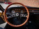 dashboard of a classic car with a wooden steering wheel and gauges