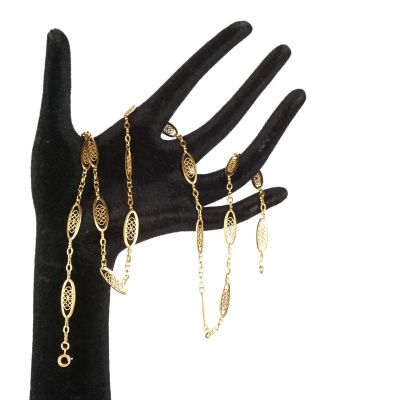 la main tient un bracelet à chaîne en or et un bracelet à chaîne en or