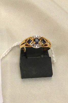 un gros plan d'une bague en or sertie de saphirs bleus