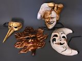 three masks are sitting on a table with a hand holding one of them