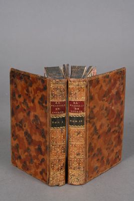 an old book opened to show two books on a gray surface