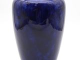un vase bleu posé sur une surface blanche
