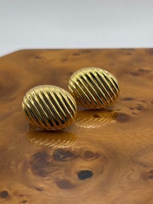 des boucles d'oreilles à tige plaquées or posées sur une table en bois, sur fond blanc