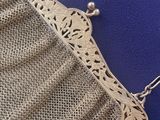 a close up of a silver purse on a blue surface