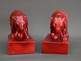 paire de serre-livres en forme d'éléphants en céramique rouge, posés sur des socles en marbre rouge