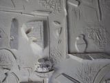 a white wall with carvings on it and a clock on the wall