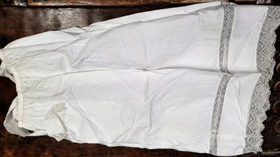 une photo d'une chemise blanche bordée de dentelle posée sur une table en bois
