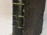 an old book sitting on top of a white cloth covered table