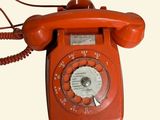 a red telephone that is on a white surface