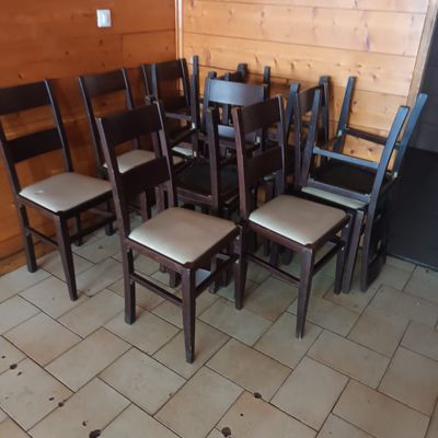 several wooden chairs are lined up against a wall in a restaurant