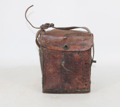 an old brown leather bag with a metal handle on a white surface