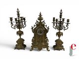 three candles and a clock sitting on a table