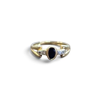 un gros plan d'une bague en or sertie d'une pierre noire et de diamants
