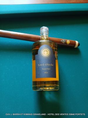 une bouteille d'alcool et un cigare posés sur une table de billard