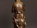 bronze statue of a woman holding a child on a wooden table