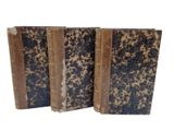 two old books are stacked on top of each other on a white surface