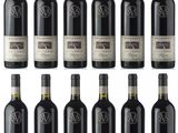 six bottles of red wine are lined up on a white surface