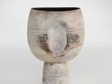 un vase blanc bordé de noir posé sur une surface blanche